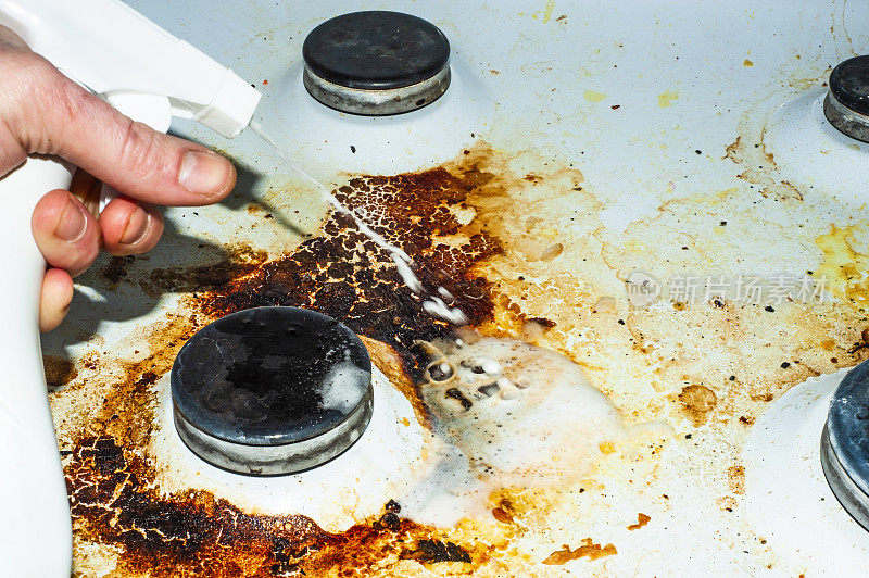 用剩菜弄脏炉子。不干净的燃气厨房灶台上有油腻的斑点，旧的脂肪渍，油炸的斑点和油飞溅