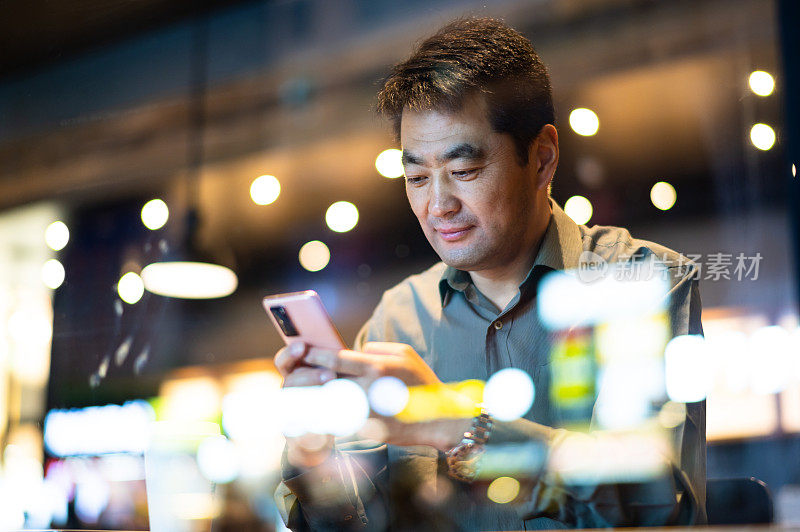 亚洲中年男子在咖啡店使用智能手机