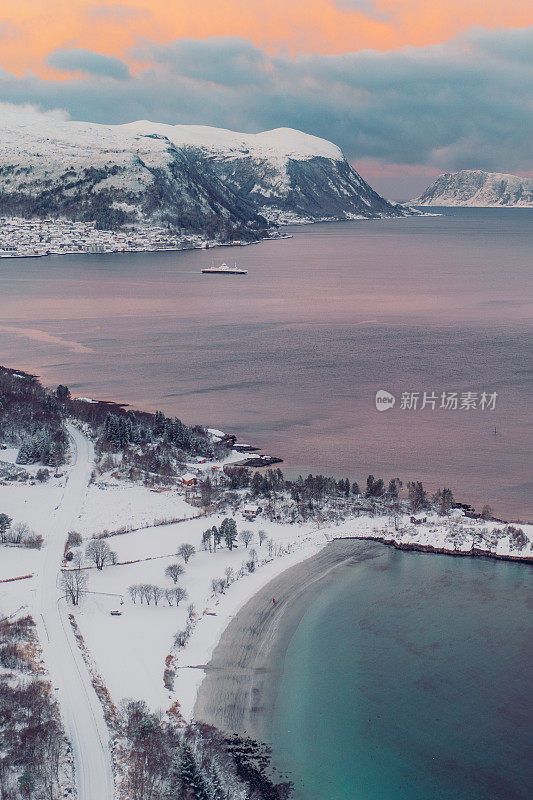 航拍图像的女人和男人走在风景秀丽的turqouse海滩在雪与山景在挪威