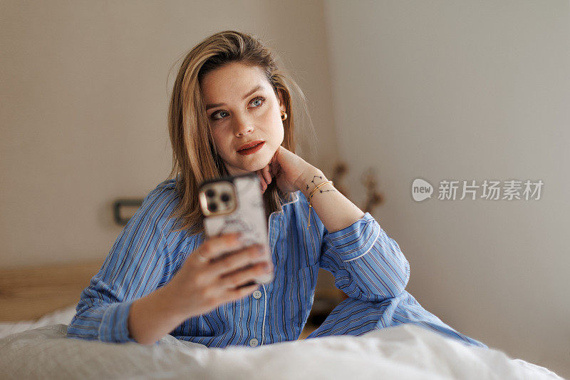 年轻快乐的女人在她的床上拍照。