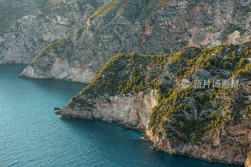 在希腊，岩石峭壁和平静的蓝色大海的迷人景色