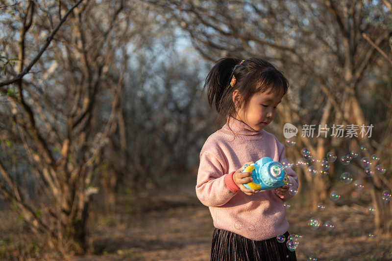 一个小女孩正在森林里用泡泡玩具吹泡泡