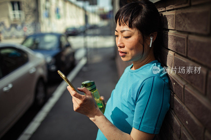 一名年轻的日本女子在健身后使用智能手机休息