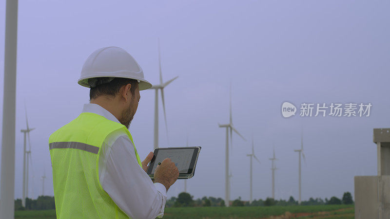 一名工程师在风力涡轮机农场研究用于分析和开发风力发电的数字平板电脑
