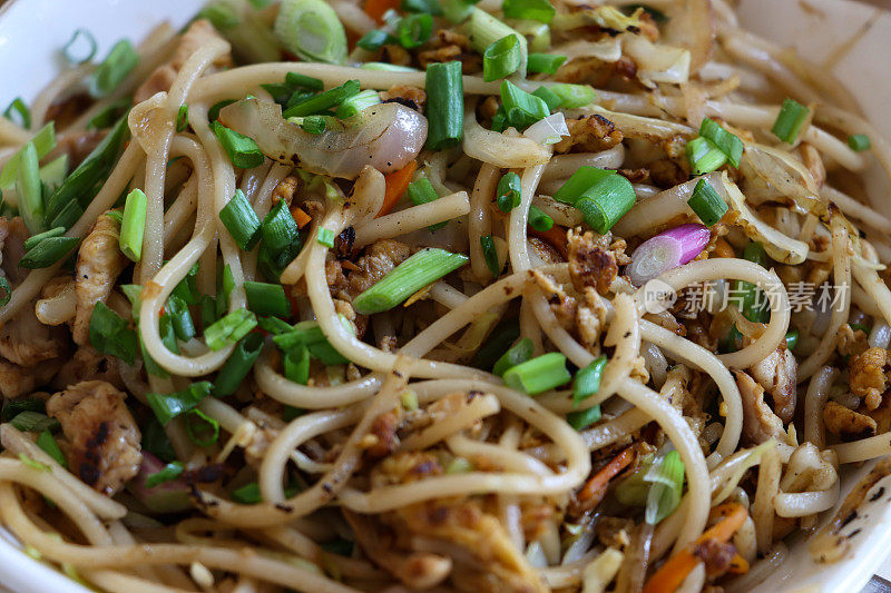 全画幅亚洲鸡肉炒面面，鸡胸肉块，红色和小葱，中国外卖餐厅的食物，外卖餐在白色的盘子，高架视图，重点在前景