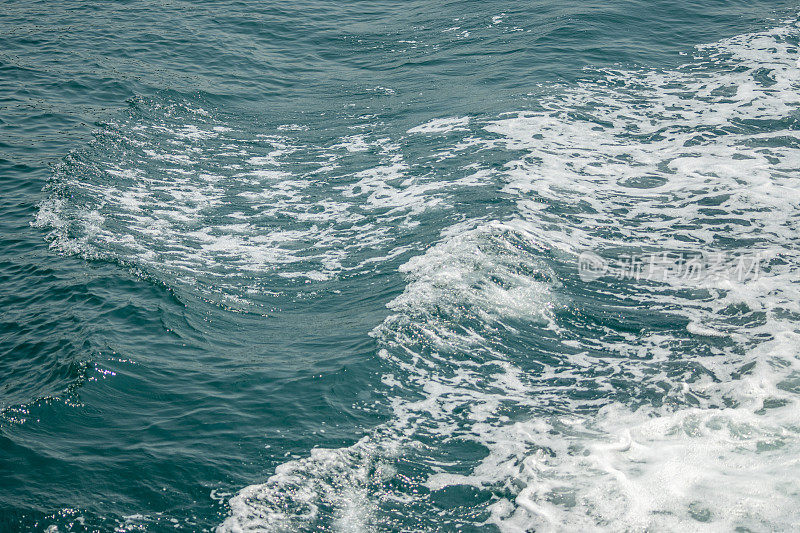 卷曲的海浪和白色的泡沫溅在海面上。清澈的蓝绿色海水