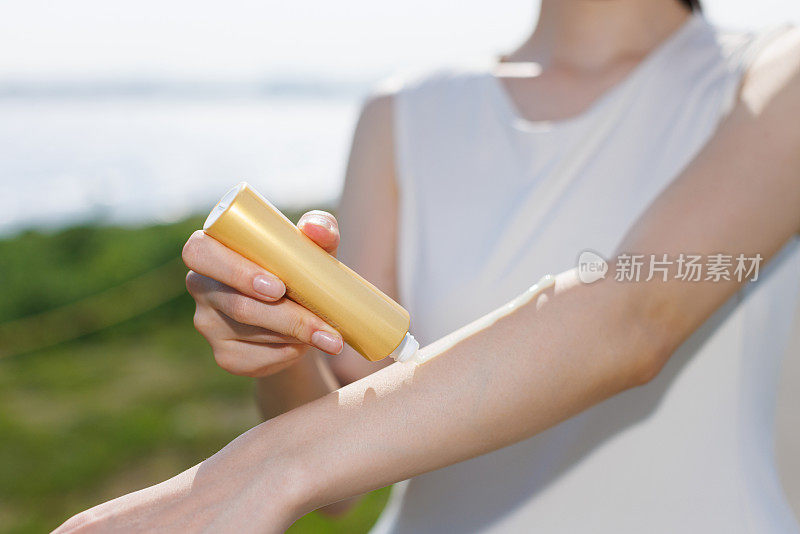 年轻的亚洲女性在手上涂防晒霜
