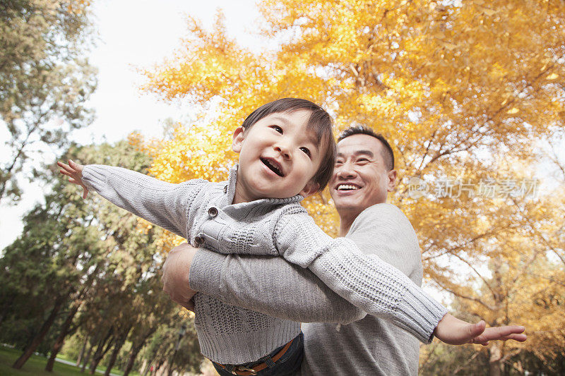 父亲和儿子一起在公园里玩秋天