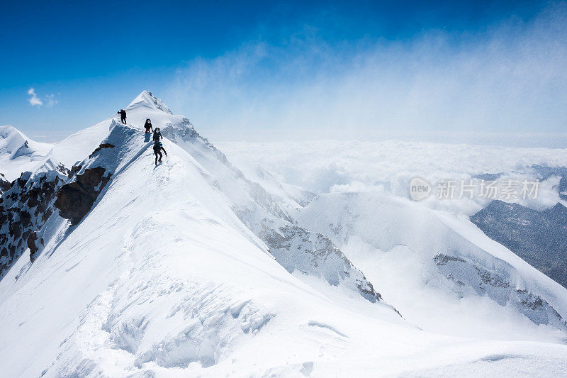 登山者在暴风雪中在狭窄的山脊上保持平衡