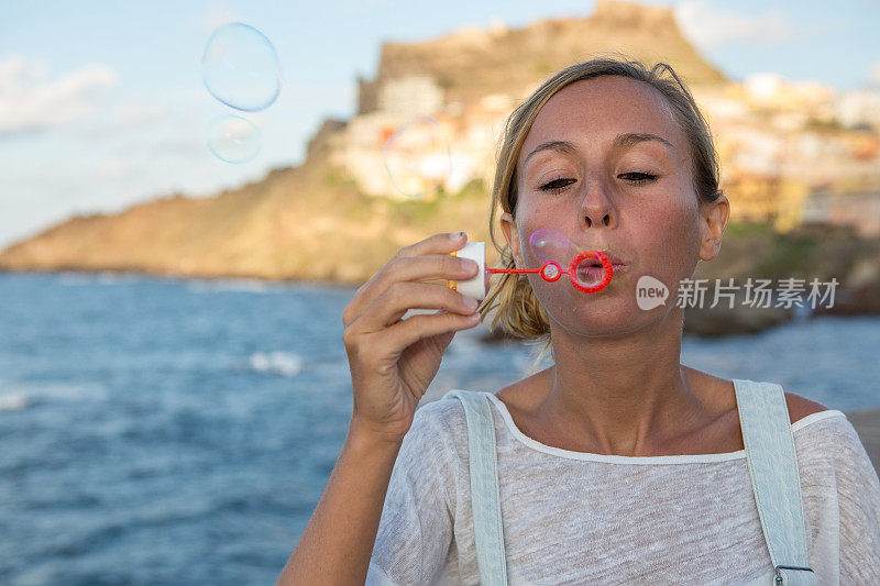 意大利，日落时分，年轻女子在户外吹泡泡