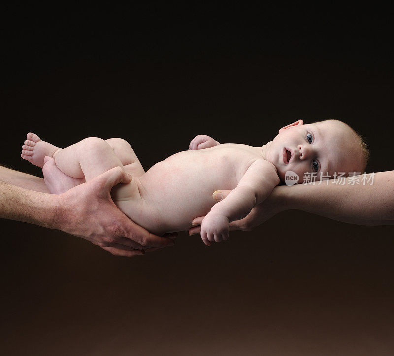 赤裸的男婴挂在他父母的手中