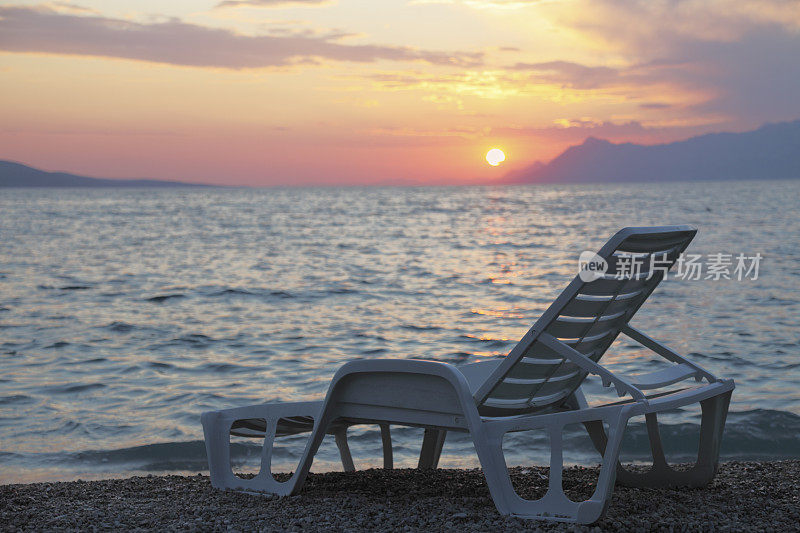 地中海夕阳下孤独的白色塑料日光浴床