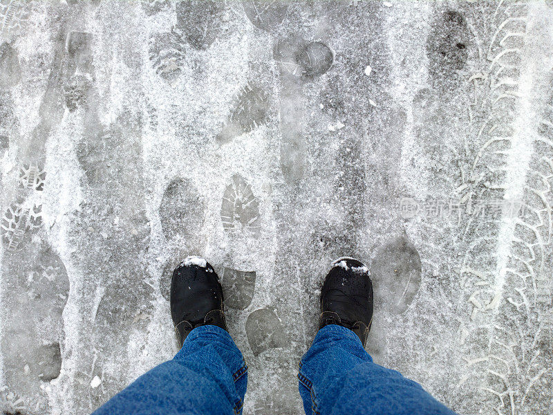 脚踩在雪地里的柏油路上。