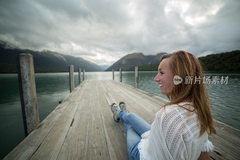 年轻女子坐在湖边的码头上看风景