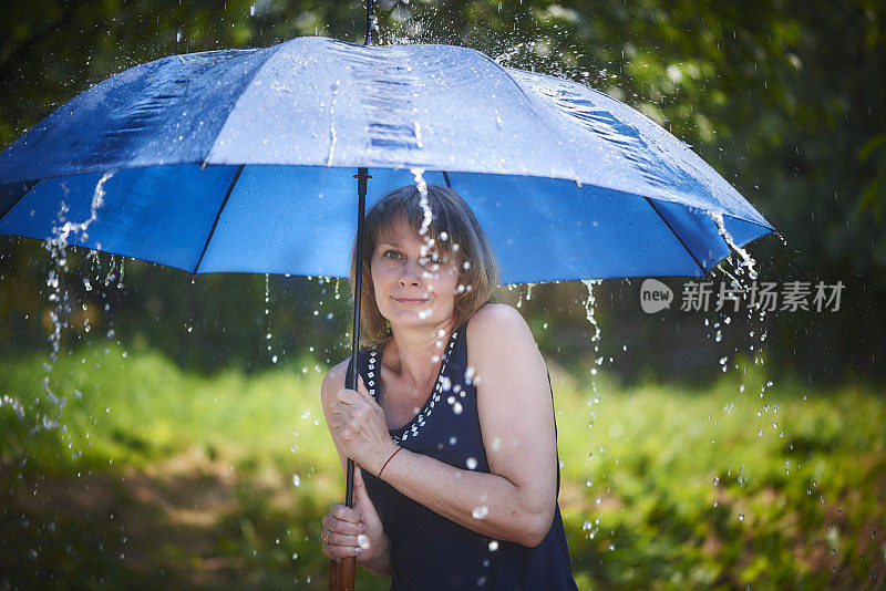 美丽的金发女人在雨中撑着伞