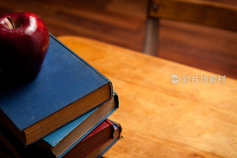旧课桌，在硬木地板上放着书和苹果