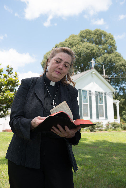 女牧师在教堂前读圣经