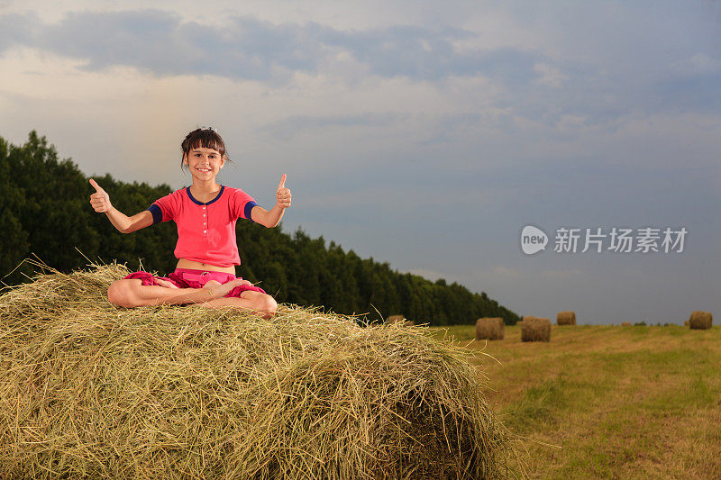 小女孩坐在干草捆上摆莲花姿势