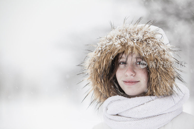 雪下穿着白色夹克的漂亮少女