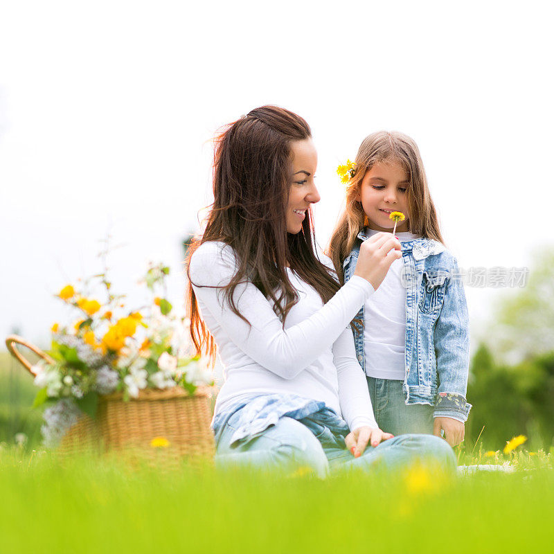 母亲和女儿在大自然中闻着花香