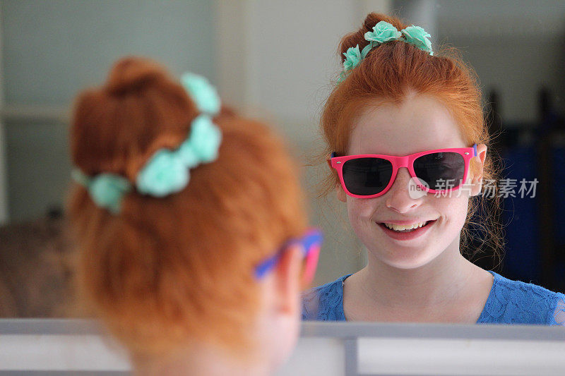 红发髻的女孩，看着镜子，戴着墨镜