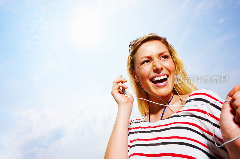 一个欢快的年轻女子正在用她的MP3听音乐