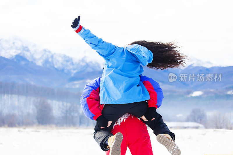 在雪地里骑马的夫妇的后视图