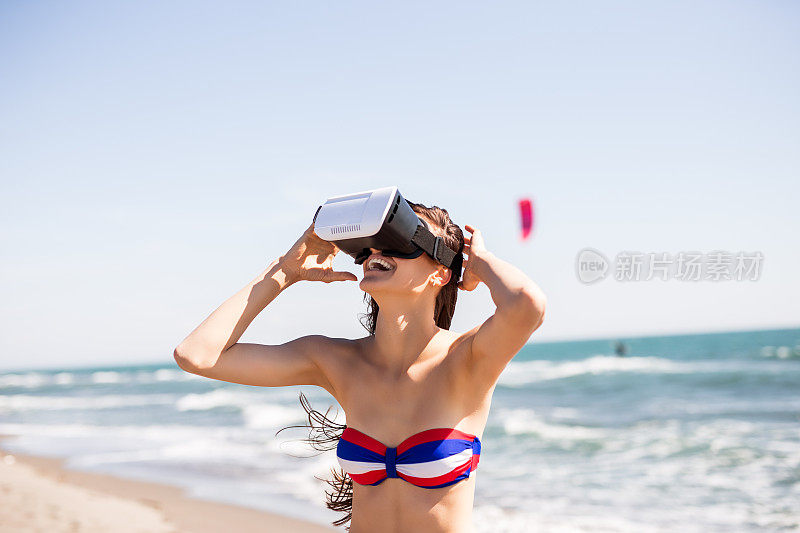 女人在海滩上通过VR设备观看。夏日理念，朋友，友谊，夏日乐趣，年轻人玩得开心