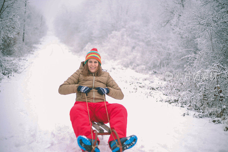 快乐的年轻女子在一个快速的雪橇骑下冰冷的斜坡