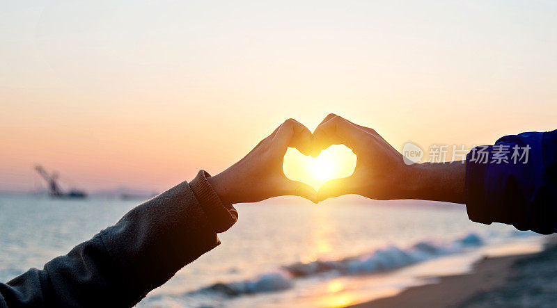 双手在沙滩上创造一颗心