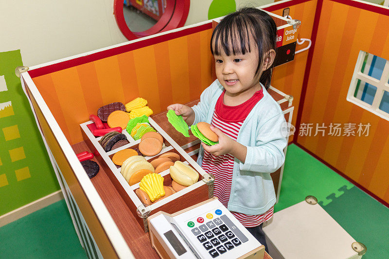 亚洲华人小女孩在汉堡店扮演角色