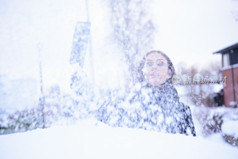 冬天即将来临。女人在冰冷的天气里，车被雪覆盖着。