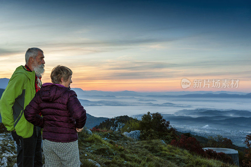 快乐的老年夫妇远足在秋天的黎明在朱利安阿尔卑斯山，斯洛文尼亚，欧洲