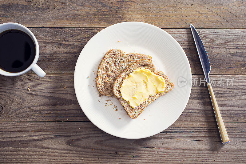 把涂了黄油的面包切片放在木桌上