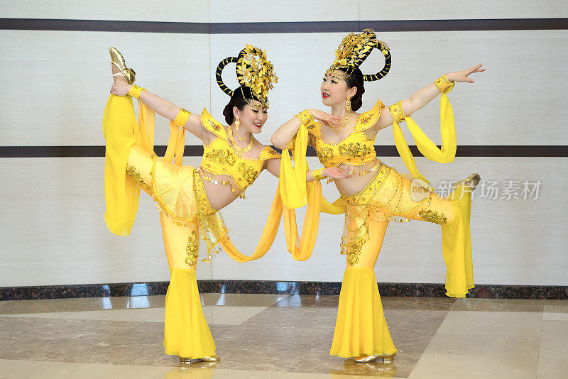 两个漂亮的女孩穿着黄色的中国传统舞台服装