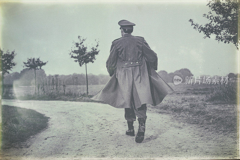 古色古香的黑白照片，1940年代的军官走在乡村道路上。后面的观点。