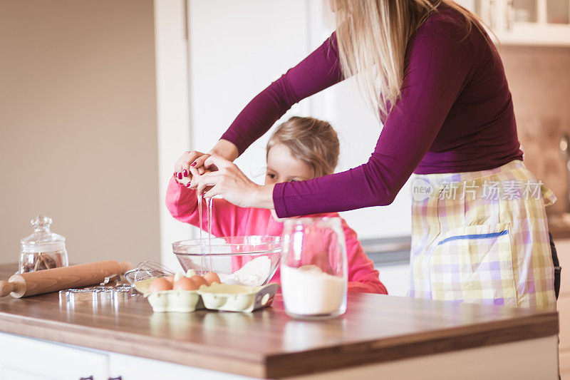 家庭的时刻。快乐的年轻女孩和她的母亲有乐趣在厨房，做饼干。