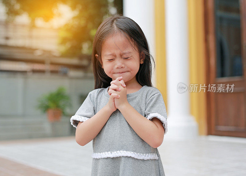 闭上眼睛，小亚洲女孩在教堂祈祷。