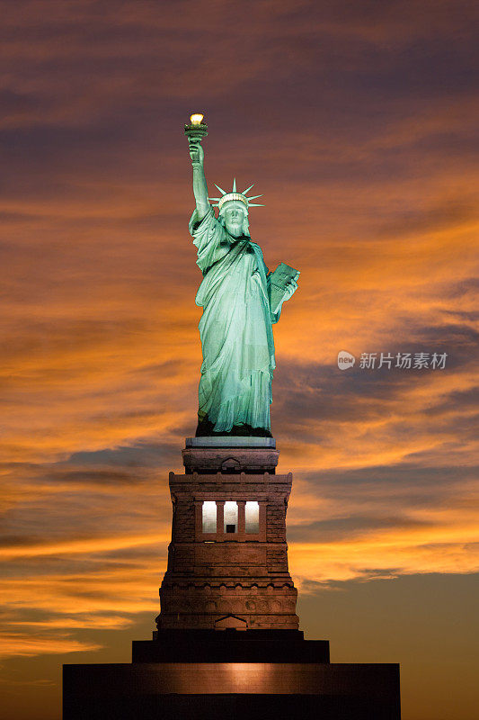 自由女神像在日落与蓝色和黄色的天空，纽约市。