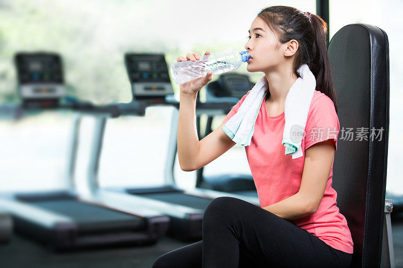 亚洲女性在健身房锻炼后喝水。