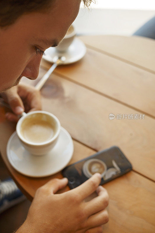 学生使用触摸屏智能手机，一边喝咖啡一边上网。