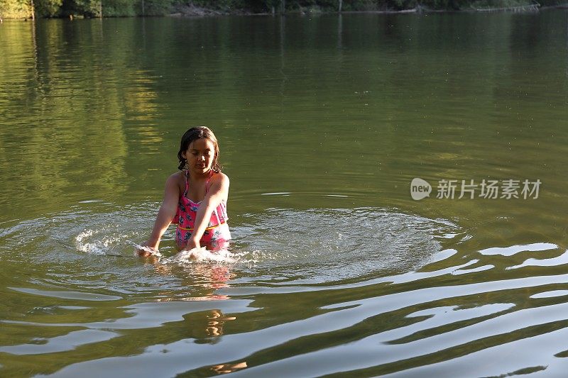 女孩走进淡水湖，在一根圆木上保持平衡