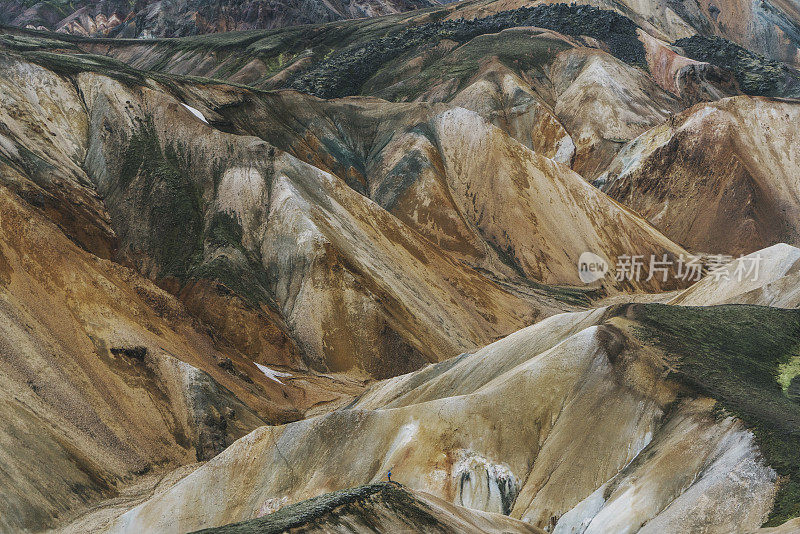 在冰岛的Landmannalaugar，一名妇女在彩色山脉附近徒步旅行