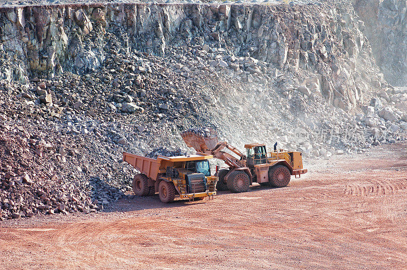 在采石场里，自卸车由挖掘机装载