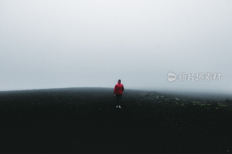 穿着红色夹克的人徒步穿越冰岛的火山景观和风