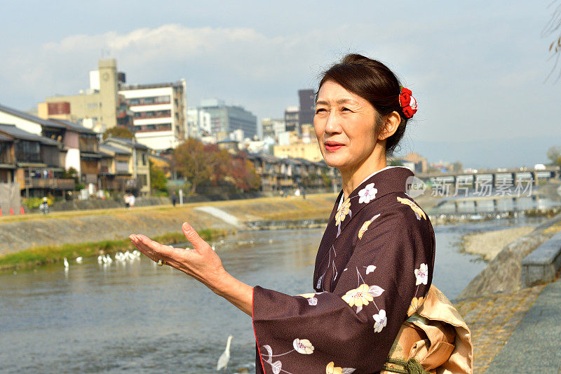 穿着和服的日本妇女在京都的秋天沿着加茂河行走