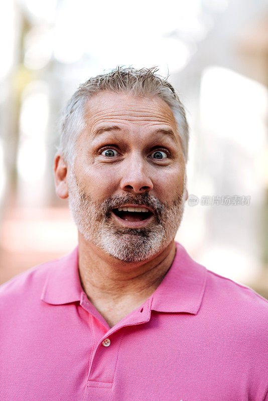 肖像成熟的白人男子灰色头发在粉红色polo衫与愉快的面部表情
