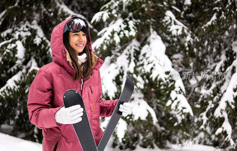 快乐的女人拿着滑雪板，准备滑雪