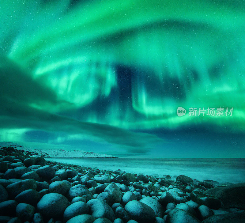 海洋上空的北极光。俄罗斯捷里别尔卡的北极光。星空，极地的光和云。夜晚冬天的风景有美丽的极光，海与冻结的石头在模糊的水。旅行