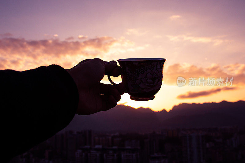 夕阳西下，男人的手握着咖啡杯